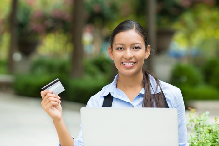 Portrait happy young business woman holding credit card and laptop making online oder, shopping concept isolated outdoors, outside background. Positive facial expressions, emotions. Smiling customer-1