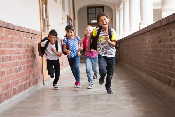 Cute pupils running down the hall at the elementary school